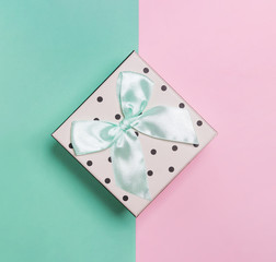 Small giftbox with bow on pastel color background,