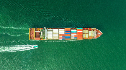 Aerial veaw a Large container ship is leaving the port full loaded with containers and cargo.