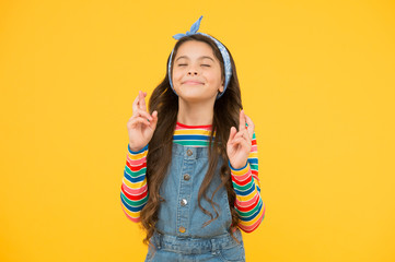 Child dream. Hopeful concept. Small child with long hair in casual fashion. Hope for best. Believe in herself. Cute child make wish yellow background. Little child keep fingers crossed for luck