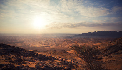 Desert Landscape of Al FAYA Dubai-UAE, with a sunset, stones, bushes and the sky.