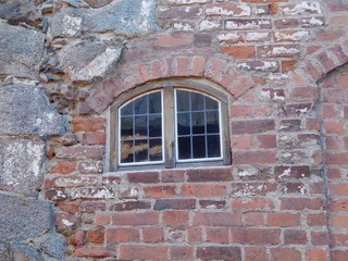 Fototapeta na wymiar Wall of a medieval castle of stone and brick and a window in it