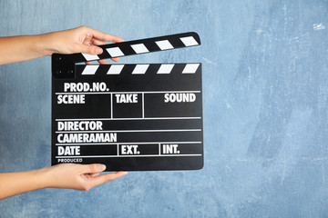 Obraz premium Woman holding clapperboard against color wall, closeup with space for text. Cinema production