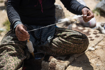 Hands of a woman spinning wool fibres
