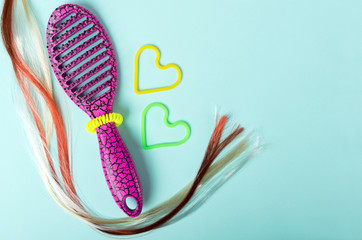 Top view of colorful hair, pink brush and scrunchies on the blue background.Free space for design