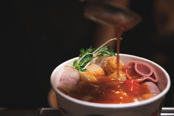 Pour spicy sauce into Delicious shabu put in paper bowl with many meatball different shape in Japanese style - Vertical photo