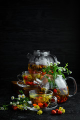 Chamomile and wild rose tea. Hot winter drinks. On a black background. Top view.