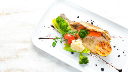 Baked trout fillet with vegetables on a plate. Top view. Free copy space.