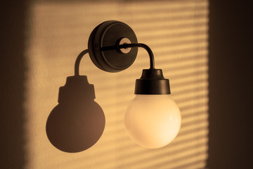 Lighted classic sconce of round shape on the wall, with soft light and diffused shadows
