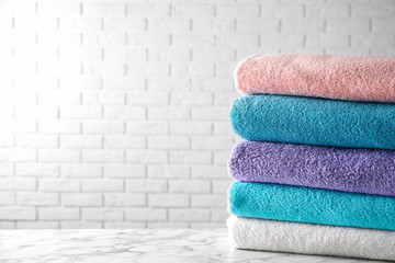 Stack of clean bath towels on white marble table. Space for text