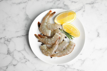 Fresh raw shrimps with lemon and rosemary on marble table, top view