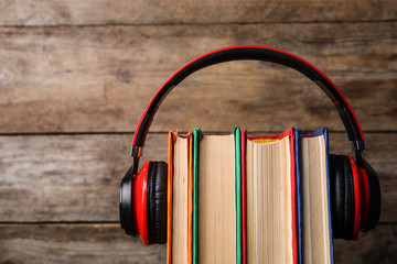 Books and modern headphones on wooden background, closeup