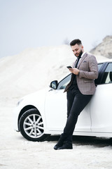 guy businessman in car with laptop and phone