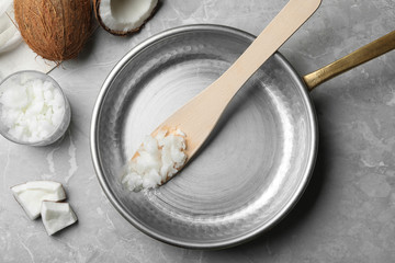 Flat lay composition with coconut oil and frying pan on grey marble table. Healthy cooking