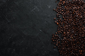 Roasted coffee beans. On a black stone background. Top view. Free space for your text.