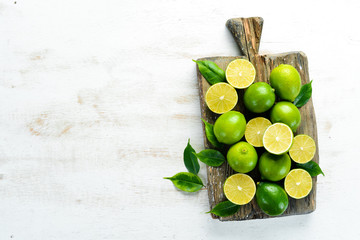 Green limes on white wooden background. Fruits. Top view. Free space for your text.