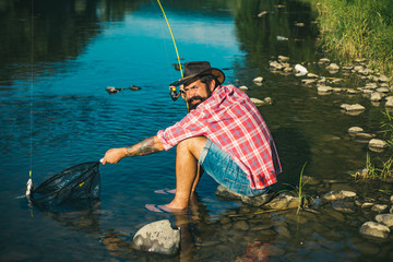 Man in shirts fishing with net and rod during the morning light on the lake. Fish on hook. Fisher fishing equipment. Sports fishing. Fishing. Hunting. Hobby and sport activity.
