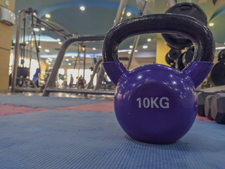 Naklejka na ściany i meble Losing weight and increasing strength by doing the exercises with 10 kg weight ball dumbbell on a gym rubber floor in a modern gym