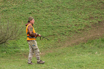 Hunting period, autumn season open. A hunter with a gun in his hands in hunting clothes in the autumn forest in search of a trophy. A man stands with weapons and hunting dogs tracking down the game.