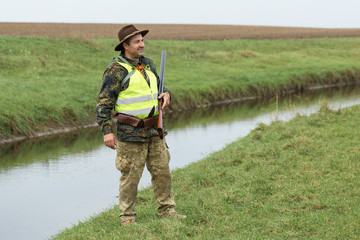 Hunting period, autumn season open. A hunter with a gun in his hands in hunting clothes in the...