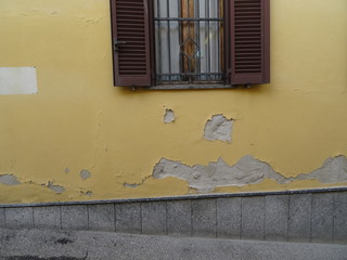 Detail of the window with bars on a facade plastered with yellow