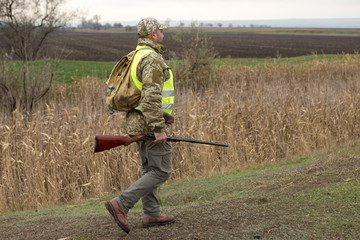 Hunting period, autumn season open. A hunter with a gun in his hands in hunting clothes in the...