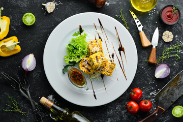 Grilled corn with sauce and vegetables on a plate. Top view. Free copy space.