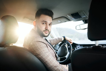 guy businessman in car with laptop and phone