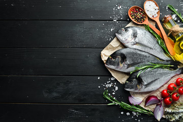 Raw dorado fish with lemon and spices on a black background. Top view. Free space for your text.