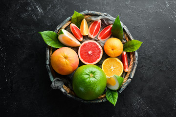 Fresh citrus fruits on black stone background. Top view. Free copy space.