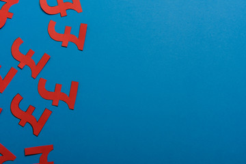 Paper yellow symbols of british pound currency on blue background. View from above with copy space.