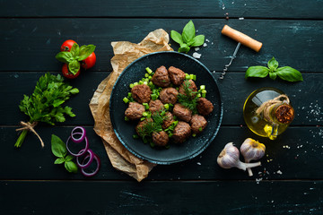Baked meat balls with onions on a black plate. Top view. Free copy space.