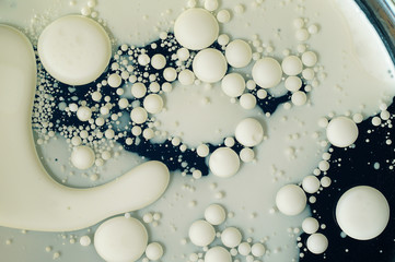 Milk and vegetable oil mixed together and forming an abstract pattern on a blue background. Trending color, horizontal layout, top view.