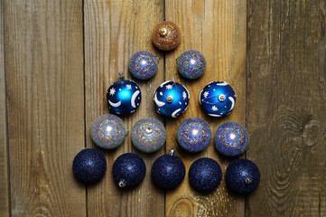 Alternative Christmas tree of blue, silver, shiny Christmas decorations-balls lying on a textured, wooden background . Close-up, horizontal layout, copy space.