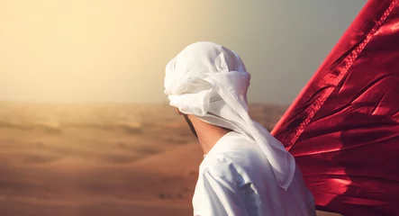 Foto op Canvas arab man holding flag walking alone in the desert © Moez
