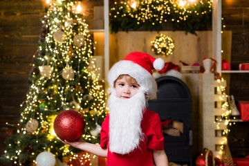 Fototapeta na wymiar Happy child decorating Christmas tree. Happy little child dressed in winter clothing think about Santa near Christmas tree.