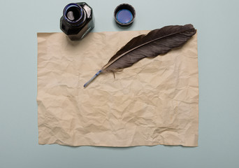 Raven feather, inkwell and old yellowed paper on red background. Copy space.