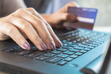 hand holding credit card and using computer for online shopping