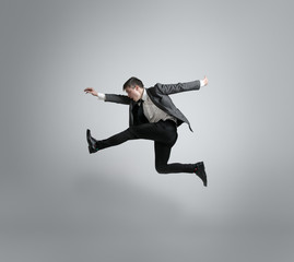 Fototapeta na wymiar Time for movement. Man in office clothes running, jumping isolated on grey studio background. Businessman training in motion, action. Unusual look for sportsman, new activity. Sport, healthy lifestyle