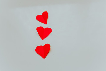 Three red paper hears on the light grey background. Saint Valentine s Day concept. 