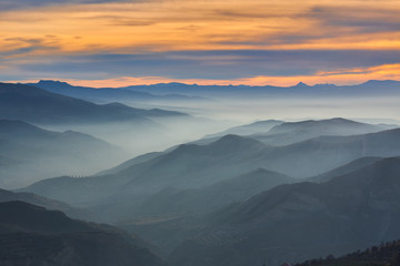 Obraz premium Winter landscape of the Sierra Nevada natural park at sunset with fog banks between the mountains.