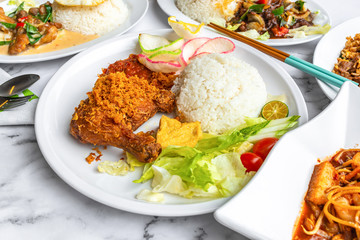 Ayam Penyet is Indonesian, East Javanese cuisine - consisting of fried chicken that is smashed with the pestle against mortar to make it softer, served with sambal chilli. Food on table concept.