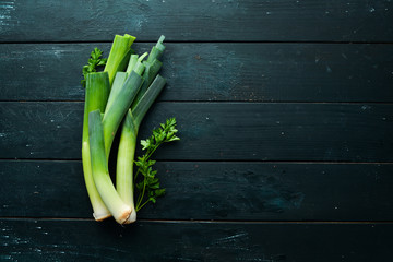 Raw green leek on black background. Vegetables for healthy eating. Top view. Free copy space.