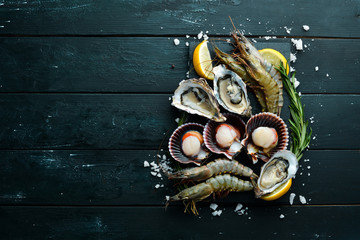 Seafood. Oysters, scallops, shrimp. Top view. On a black background. Free copy space. - obrazy, fototapety, plakaty