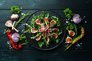 Obraz na płótnie Canvas Arugula salad, tuna fillet and figs with blackberry berries. Menu. Free copy space. Top view.
