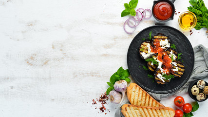Baked eggplant with caviar and feta cheese on a black plate. Flat lay. Top view. Free copy space.