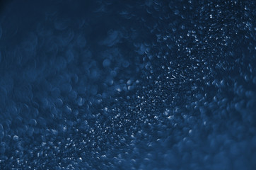 Classic Blue color. Color of the year 2020. Abstract festive bokeh background with shining defocus sparkles. Blurred glitters shimmering dust macro close up, copy space for text logo