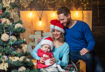 Joyful baby with parents open Christmas gift at home. The morning before Christmas for christmas family.