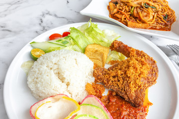 Ayam Penyet is Indonesian, East Javanese cuisine - consisting of fried chicken that is smashed with the pestle against mortar to make it softer, served with sambal chilli. Food on table concept.