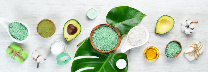 Cosmetics from avocado, avocado oil, sea salt and face cream, on a white wooden background. The concept of cosmetics and spa. Top view. Free copy space.