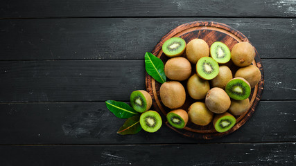 Fresh kiwi and green leaves on the table. Rustic style. Fruits. Top view. Free space for text.